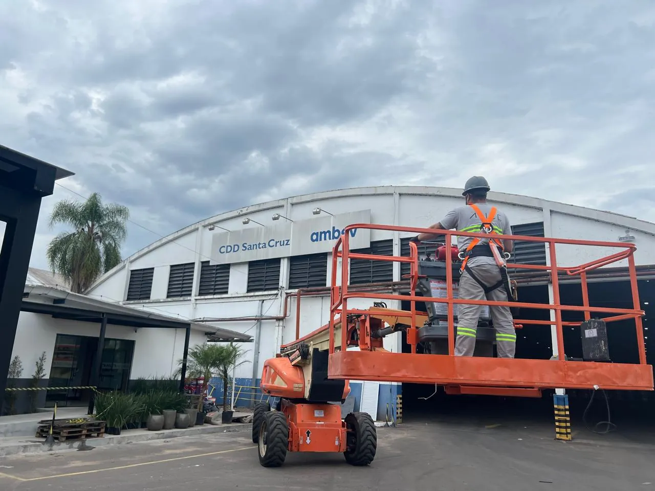 Profissional da Ápice, com cinto de segurança, em plataforma elevatória durante a obra do acesso do CDD Ambev Santa Cruz do Sul.